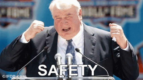 Man In Suit At Podium With Safety Above GIF