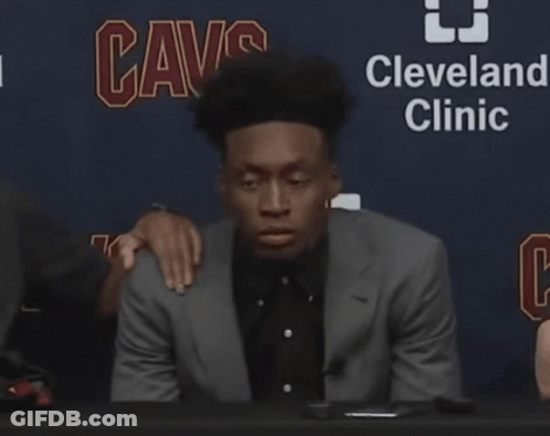 Man In Suit At Table In Front Of Cleveland Clinic Sign GIF