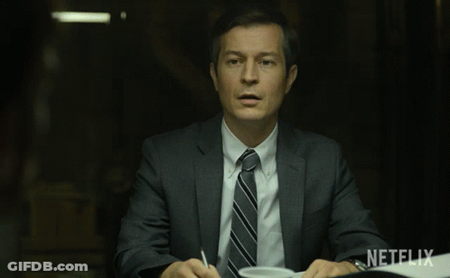 Man In Suit At Table With Netflix Logo GIF
