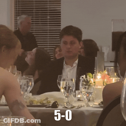 Man In Suit At Table With Wine And 5-0 GIF
