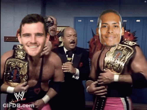 Man In Suit Behind Two Wrestlers Holding Belts GIF