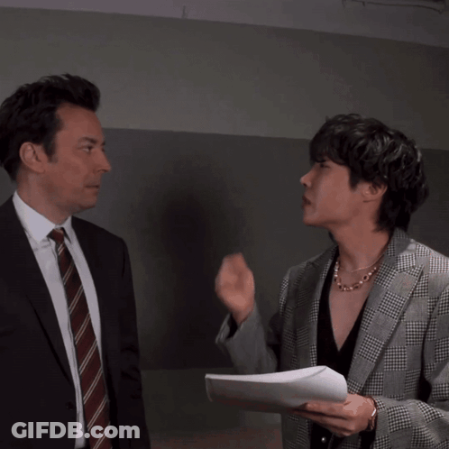 Man In Suit Blowing Kiss To Man In Plaid Jacket GIF
