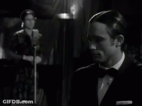 Man In Suit Clapping While Woman At Microphone Black And White GIF