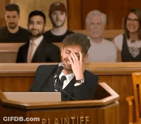 Man In Suit Covering Face At Podium GIF