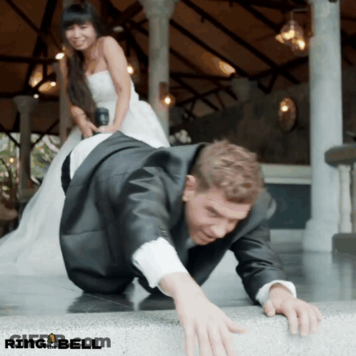 Man In Suit Crawling, Woman In Wedding Dress Standing Behind GIF