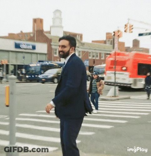 Man In Suit Crossing Street In Front Of Imgplay Building GIF