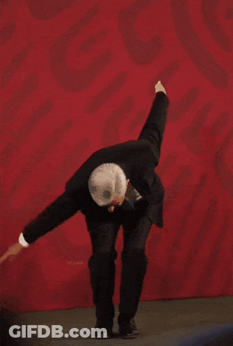 Man In Suit Dancing Before Red Wall With Mexico GIF