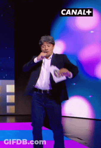 Man In Suit Dancing In Front Of Canal+ Sign GIF