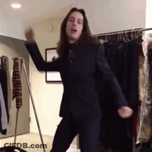Man In Suit Dancing In Front Of Clothes Rack GIF
