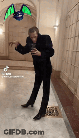 Man In Suit Dancing In Hallway With Bat GIF