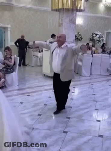 Man In Suit Dancing In Room With People Sitting GIF