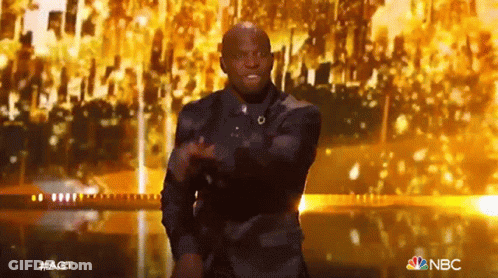 Man In Suit Dancing On Stage With NBC Logo GIF