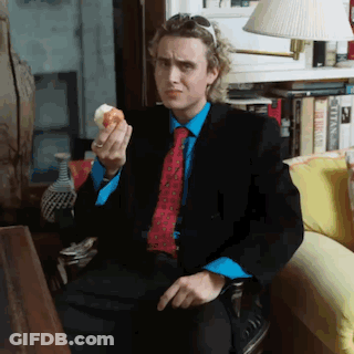 Man In Suit Eating Donut On Couch GIF