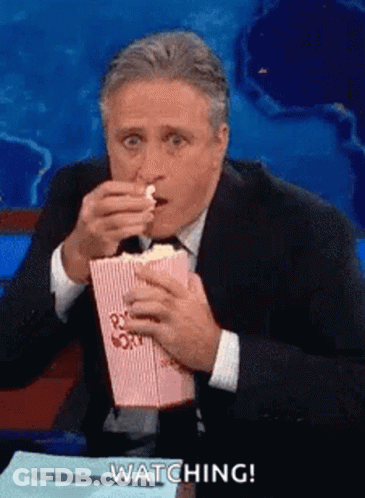 Man In Suit Eating Popcorn At Desk GIF