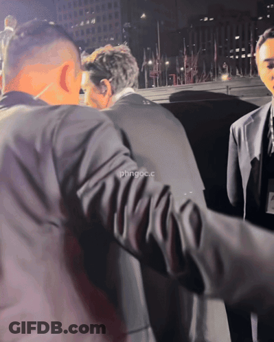 Man In Suit Escorted By Man In Black Jacket Saying Phngoc.C GIF