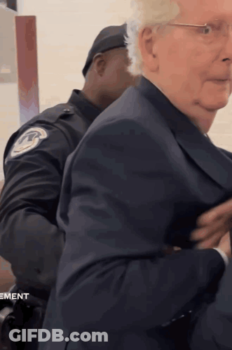 Man In Suit Escorted By Police Officer Movement GIF