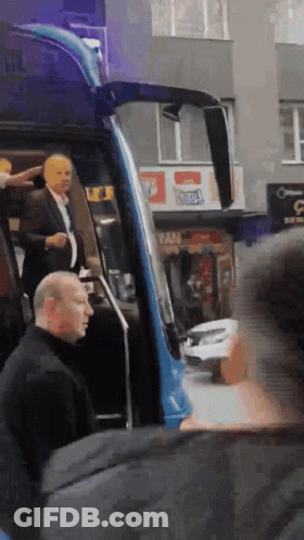 Man In Suit Exits Blue Bus At Fan Sign GIF