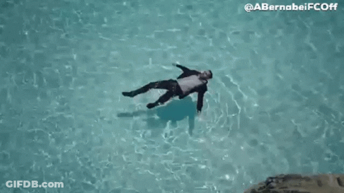 Man In Suit Floating On Back In Pool GIF