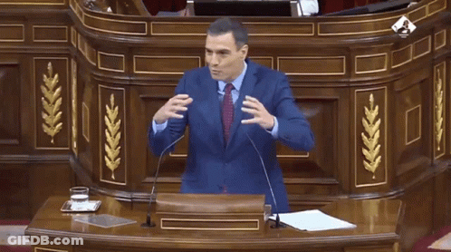 Man In Suit Giving Speech At Wooden Podium GIF