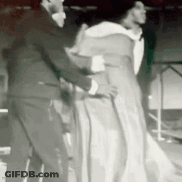 Man In Suit Helping Woman In White Dress With Cane GIF