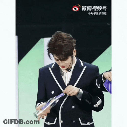 Man In Suit Holding Bottle With Chinese Writing GIF