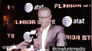 Man In Suit Holding Cell Phone At Microphone GIF