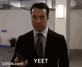 Man In Suit Holding Cell Phone Says Yeet GIF
