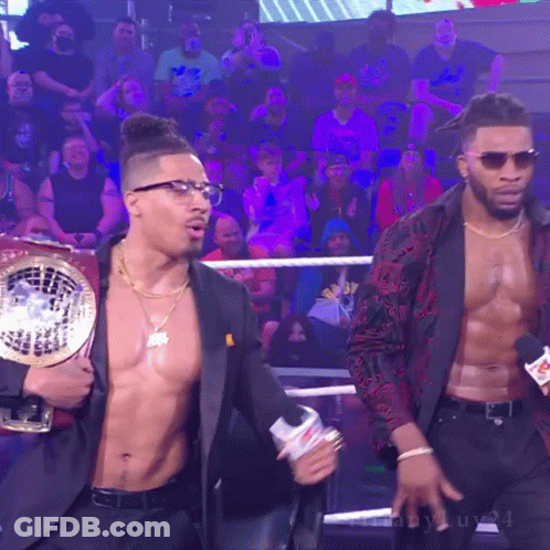Man In Suit Holding Championship Belt With Another Man Behind GIF