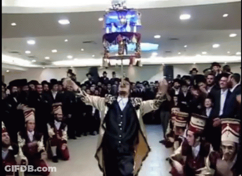 Man In Suit Holding Chandelier Over Head GIF