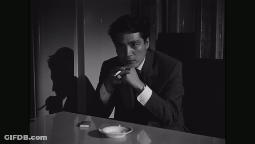 Man In Suit Holding Cigarette At Table GIF