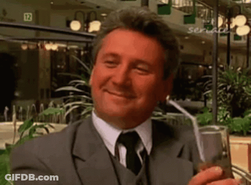 Man In Suit Holding Drink Through Straw Smiling GIF