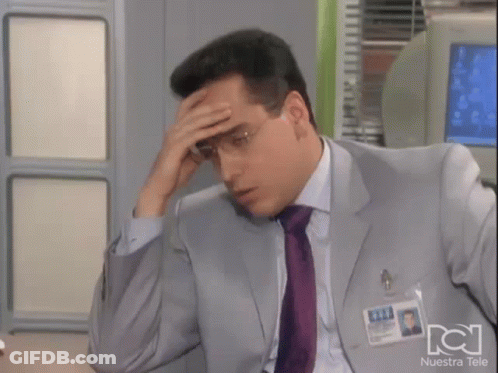 Man In Suit Holding Forehead In Front Of Nuestra Tele Sign GIF