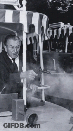Man In Suit Holding Gun By Striped Canopy GIF