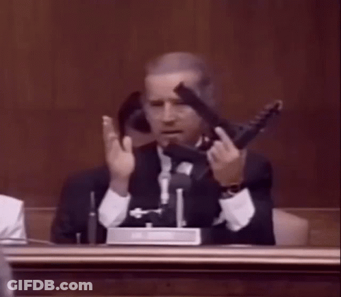 Man In Suit Holding Gun In Courtroom GIF