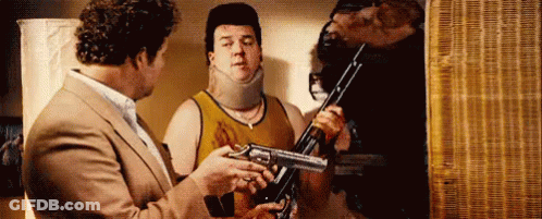 Man In Suit Holding Gun Talking To Another Man Holding Gun GIF