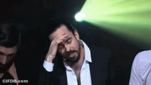 Man In Suit Holding Hand To Forehead GIF