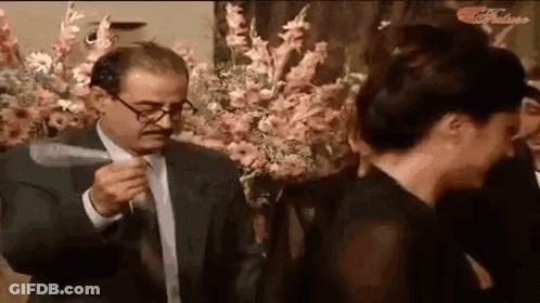 Man In Suit Holding Knife Beside Woman In Black Dress GIF