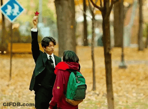 Man In Suit Holding Maple Leaf Over Girl With Green Backpack GIF
