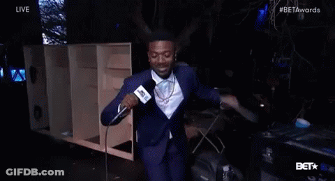 Man In Suit Holding Microphone And Smiling On Stage GIF