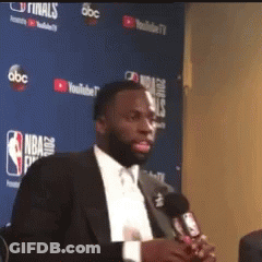 Man In Suit Holding Microphone At Blue Wall Saying NBA GIF