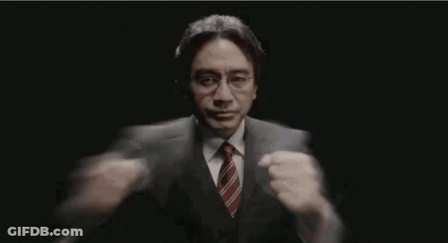 Man In Suit Holding Microphone In Dark Room GIF