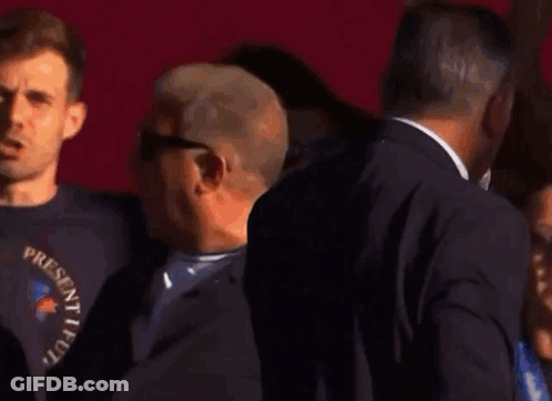 Man In Suit Holding Microphone In Front Of Group GIF