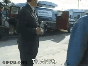 Man In Suit Holding Microphone In Front Of Van Saying Thanks GIF