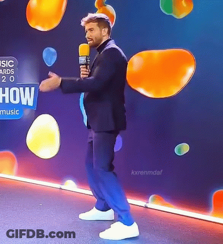 Man In Suit Holding Microphone Saying How Music GIF