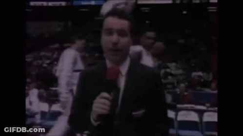 Man In Suit Holding Microphone With Bandage GIF