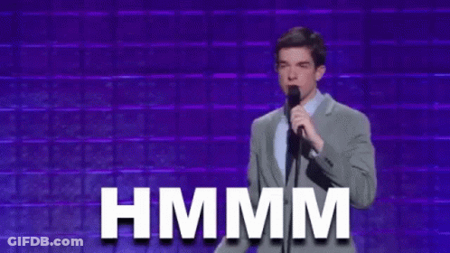 Man In Suit Holding Microphone With Gross Behind GIF