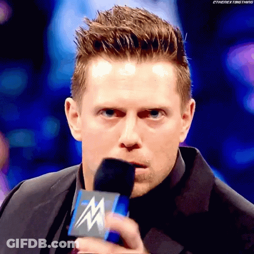 Man In Suit Holding Microphone With Letter M GIF