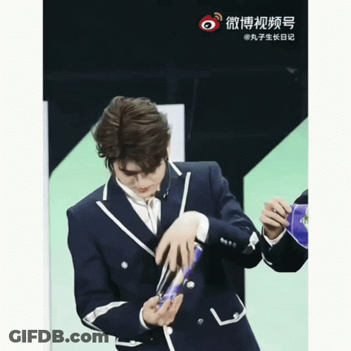 Man In Suit Holding Object With Chinese Writing GIF