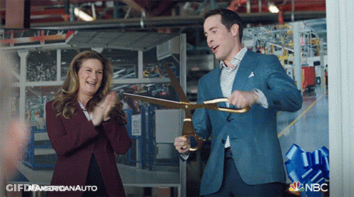 Man In Suit Holding Scissors In Front Of Clapping Woman GIF