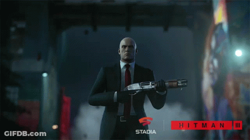 Man In Suit Holding Shotgun In Front Of Stadia Hitman III Sign GIF